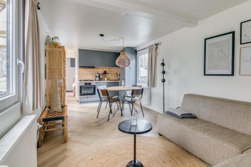 uma sala de estar com um sofá e uma mesa em Cosy 4 pers chalet midden in bos op de Veluwe em Doornspijk