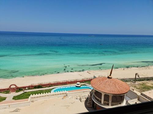 a view of the beach and the ocean from a resort at Panorama Apartment with a charming sea view near Alexandria and Burg ElArab Airport with Free Wifi شقة باطلالة ساحرة على البحر اول الساحل الشمالي واي فاي مجاني迷人海景公寓 免费无线网络 in Alexandria
