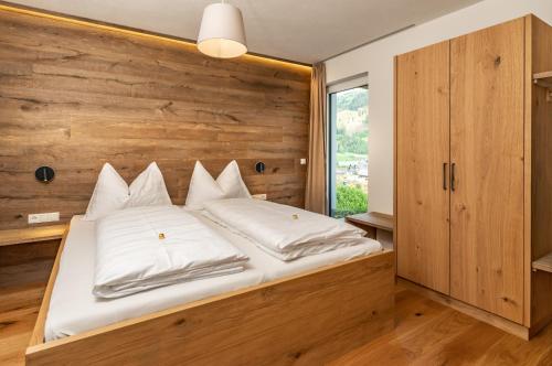 a bedroom with a large bed with a wooden wall at Alma&Antonia in Schladming