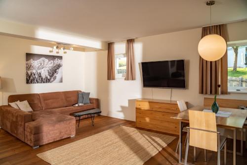 een woonkamer met een bank, een tafel en een televisie bij Haus LandArt in Schladming