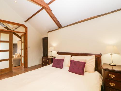 Marytavy的住宿－Nestling Barn，卧室配有一张带紫色枕头的大型白色床。