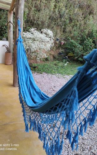 a blue hammock hanging from a porch next to water at Chalé Lavanda com Hidro, Trilhas e Cachoeiras in São Francisco Xavier