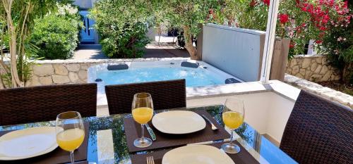 a table with glasses of wine on a patio with a hot tub at Fantasy Classic Maisonette II in Novalja