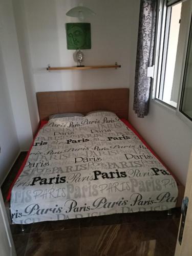 a bed in a room with a bedspread with writing on it at Apartmani Bella in Sutomore
