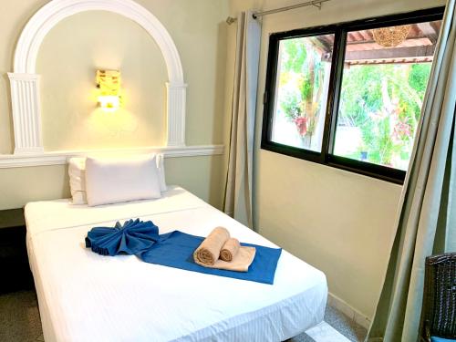 a bedroom with a bed with towels and a window at Hotel Green River in Izamal