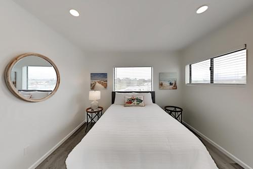 a white bedroom with a large bed and a mirror at Barefoot Wishes in Oceano