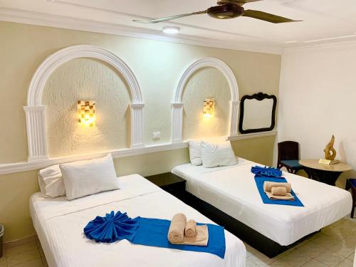 Duas camas com toalhas e chinelos num quarto em Hotel Green River em Izamal