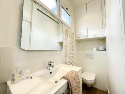 La salle de bains blanche est pourvue d'un lavabo et de toilettes. dans l'établissement Appartement Coeur de Deauville, à Deauville