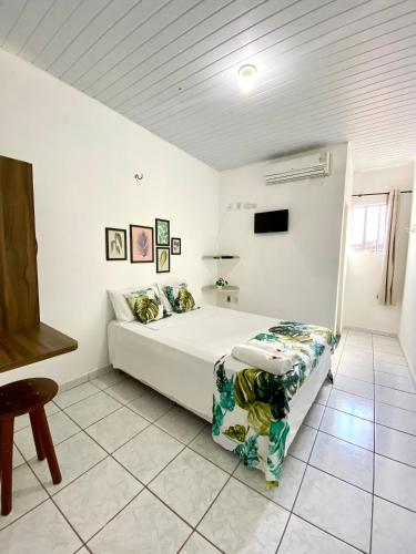 a white bedroom with a bed and a tv at Pousada Rio Alegre in Santo Amaro