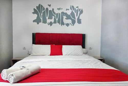 a bed with a red and white blanket on it at RUMAH KOPI SYARIAH HOTEL in Bandar Lampung