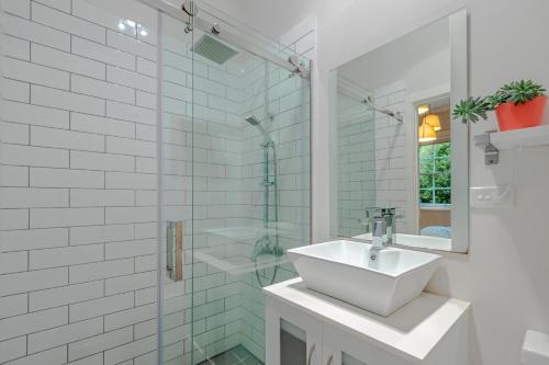 a bathroom with a sink and a glass shower at Sunshine Cottage in Katoomba