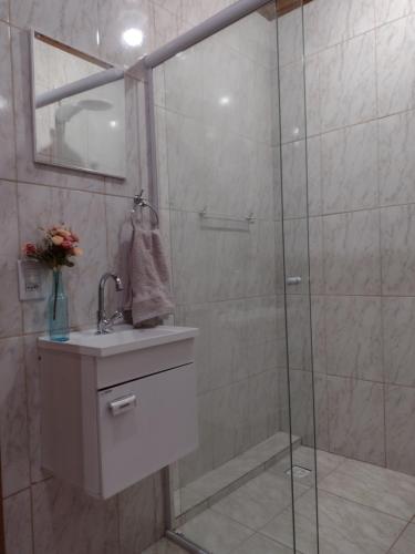 een badkamer met een douche, een wastafel en een spiegel bij Casa do Trem Suítes in Campos do Jordão