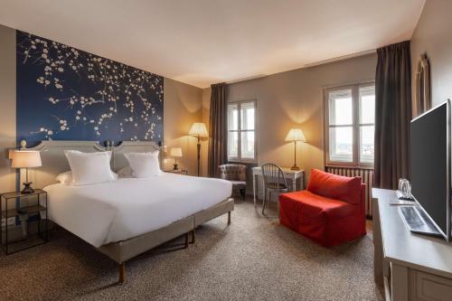 ein Hotelzimmer mit einem Bett und einem roten Stuhl in der Unterkunft Best Western Plus d'Europe et d'Angleterre in Mâcon