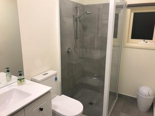 a bathroom with a shower and a toilet and a sink at Belton Apartments - The Studio in Hobart