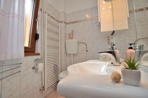 a white bathroom with a sink and a toilet at Apartment Kivi in Valbandon