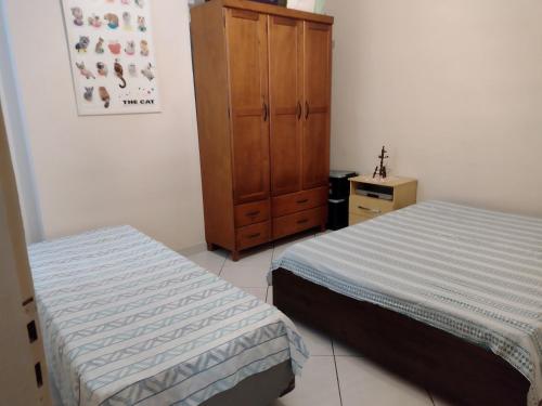 1 dormitorio con 2 camas y armario de madera en Praia, sol e lazer, en São Vicente