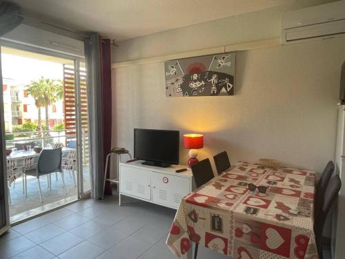 une chambre avec un lit et une télévision et un balcon dans l'établissement Appartement 2P/Cabine à Argelès-sur-Mer – Piscine chauffée, parking privé, clim, terrasse, proche mer - FR-1-225-738, à Argelès-sur-Mer