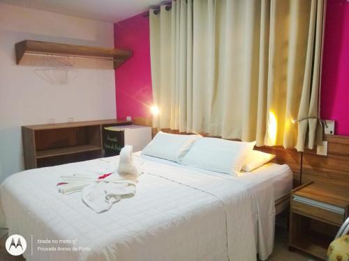 - une chambre avec un grand lit blanc aux murs roses dans l'établissement Suites Areias de Porto, à Porto de Galinhas