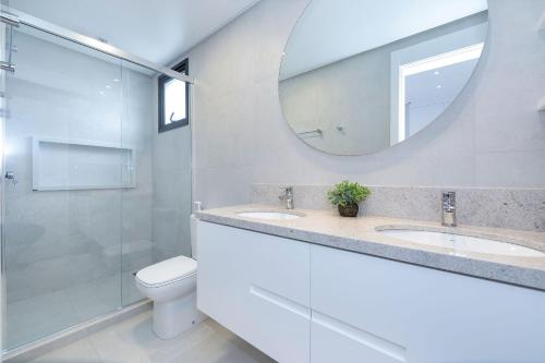 ein Badezimmer mit zwei Waschbecken, einem Spiegel und einem WC in der Unterkunft Adra 206 - Apartamento no centro de Bombinhas - Rooftop com piscina e academia - À poucos metros da praia - (Consultar serviços de roupas de cama e banho) in Bombinhas