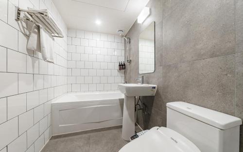 a white bathroom with a sink and a toilet at HOTEL YaJa WestGate in Cheongju