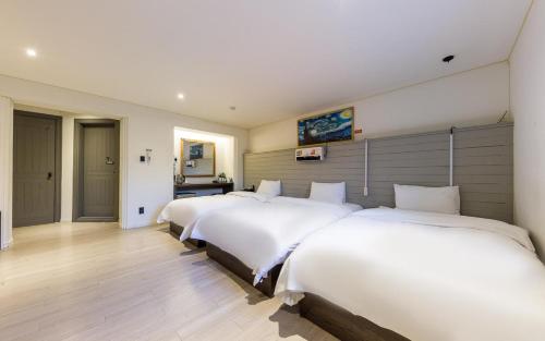 a row of four beds in a room at HOTEL YaJa WestGate in Cheongju