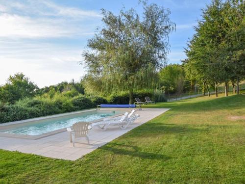 a swimming pool with two white chairs in a yard at Cosy cottage in St Medard D'excideuil with pool in Laurière