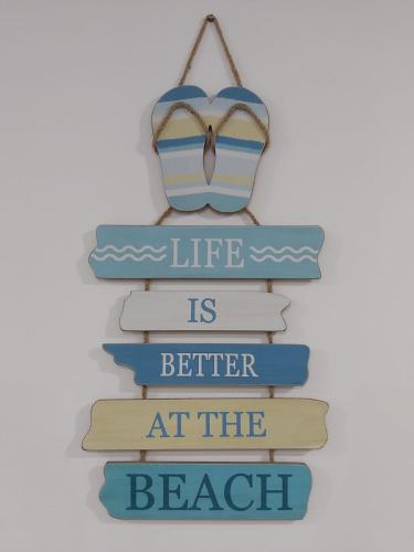 a shelf of books with a sign that reads life is better at the beach at Casa en Playa Privada - A pocos minutos de General Villamil Playas in Posorja