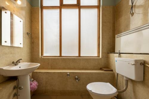 a bathroom with a sink and a toilet and a window at Primrose Cottage, 1 bhk Villa w garden by Roamhome in Leh