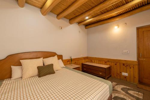 a bedroom with a bed and a dresser in it at Primrose Cottage, 1 bhk Villa w garden by Roamhome in Leh