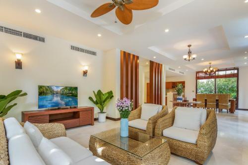 a living room with white furniture and a ceiling fan at Da Nang Paradise Center My Khe Beach Resort & Spa in Da Nang