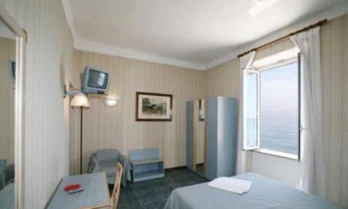 Cette chambre comprend un lit, une table et un réfrigérateur. dans l'établissement Hotel Savoy, à Varazze