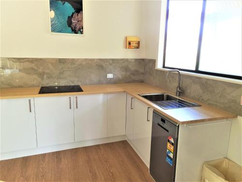 a kitchen with white cabinets and a sink and a window at Kangaroo Island - Island Beach Shack in Island Beach