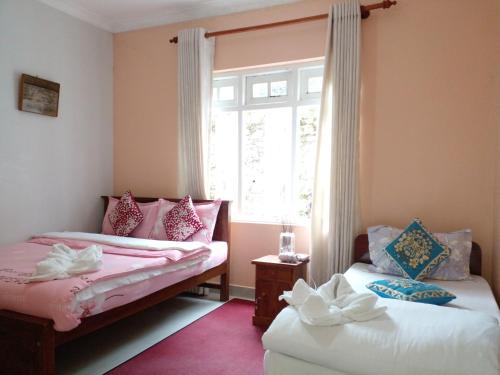 two beds in a room with a window at Vibe way (Hostel & Market farm) in Nuwara Eliya