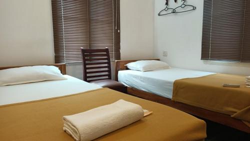 um quarto de hotel com duas camas e uma cadeira em Janatha Homestay em Cochin