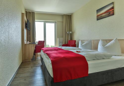 a hotel room with a large bed with a red blanket on it at Rügen-Hotel in Sassnitz