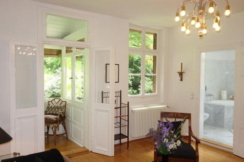 a living room with white walls and a chandelier at Bed & Breakfast Grünes Gold am Leisberg in Baden-Baden