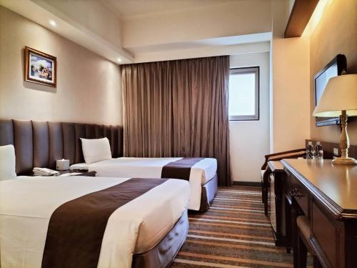 a hotel room with two beds and a desk at Urban Hotel33 in Kaohsiung
