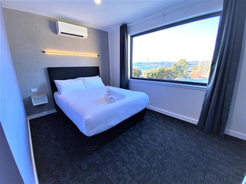 a hotel room with a bed and a large window at Vikas in Jindabyne