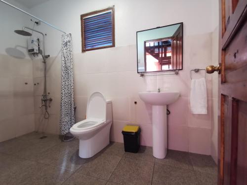 a bathroom with a toilet and a sink and a mirror at Latitude 10 Siargao in General Luna