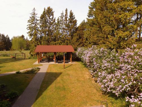 a picnic shelter in a park with purple flowers at Pilsberģu krogs in Jūrkalne