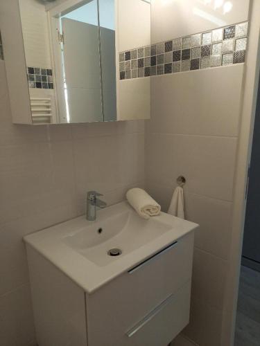 une salle de bain blanche avec un lavabo et un miroir dans l'établissement Port Soleil Naturiste, au Cap d'Agde