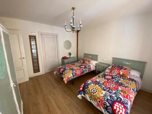 a bedroom with two beds and a chandelier at Casa MILA , Centro Histórico in Logroño