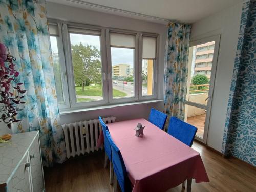 une salle à manger avec une table rose et des chaises bleues dans l'établissement Pl Zwycięstwa Centrum dla 5osób, à Piła