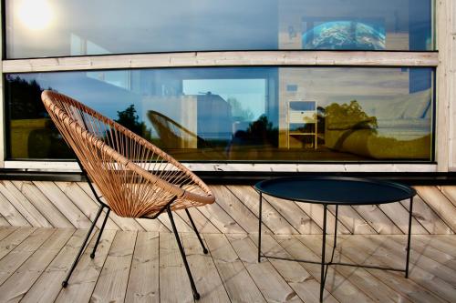 a rattan chair and a stool on a deck at Jaukūs ART stiliaus apartamentai antrame aukšte su vaizdu į marias in Svenele
