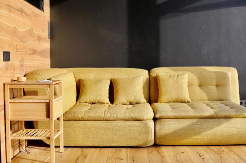 a yellow couch in a living room with a table at Jaukūs ART stiliaus apartamentai antrame aukšte su vaizdu į marias in Svenele