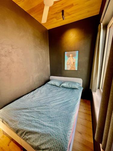 a bedroom with a bed with a blue comforter at Jaukūs ART stiliaus apartamentai antrame aukšte su vaizdu į marias in Svenele