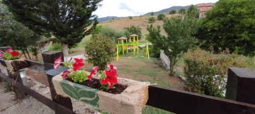 a planter with flowers in a garden with a playground at All Seasons Πέτρινες Παραδοσιακές Κατοικίες in Kalavrita