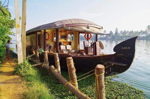a boat sitting on the water next to a dock at Sreekrishna Houseboat in Kumarakom