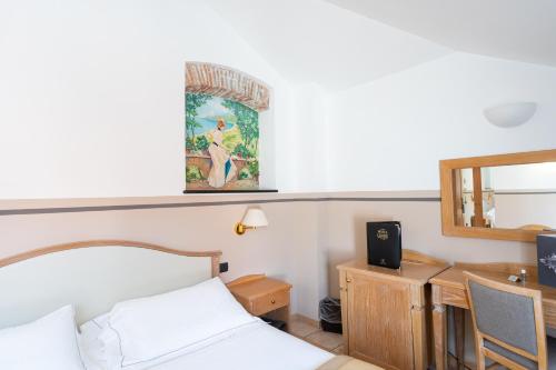 a bedroom with a bed and a desk and a mirror at Hotel Ligure in Alassio