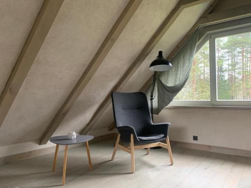 una silla negra y una mesa en una habitación con ventana en Čapu Liepu sauna, en Garkalne